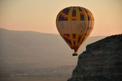 A view of the hot air balloon next to a rocky cliff at Goreme in Cappadocia, Turkey on a sunset