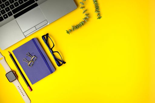 A high-angle shot of a flat lay office desk with a laptop, notebook, and smartwatches with copy space.