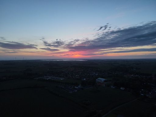 A mesmerizing view of the scenic sunset over the green landscape with buildings