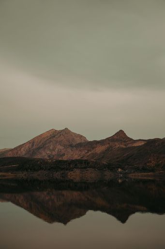 The reflection of the rocky mountains on the water against a cloudy sky