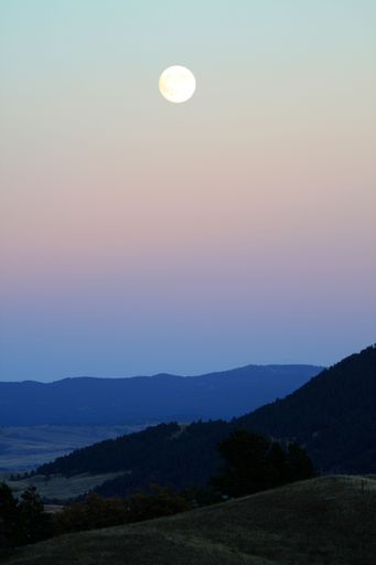 A scenic view of a mountainous landscape under a beautiful full moon