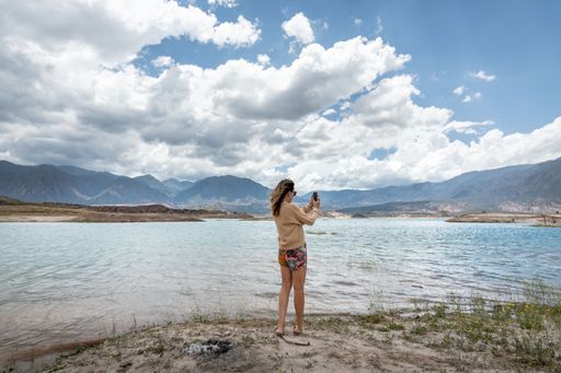 A rear view Caucasian woman taking photos of the Potrerillos lake  in Mendoza, Argentina