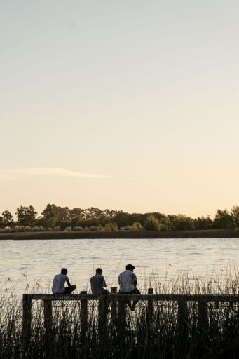 A beautiful shot of friends sitting on a pier in nature