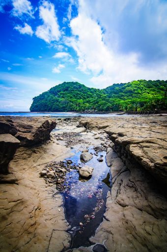 A vertical shot of a ground cut in two parts and with water in the middle under the clear blue sky