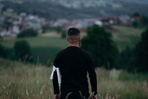 A back view of a man in a black long sleeve with a piece of white cloth tied to his upper arm