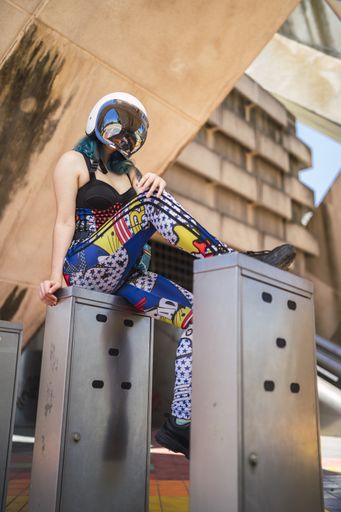 An attractive woman sitting on the metal  and wearing a motorcycle helmet