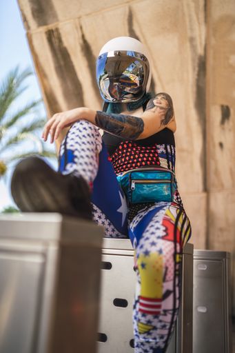 An attractive woman sitting on the metal  and wearing a motorcycle helmet