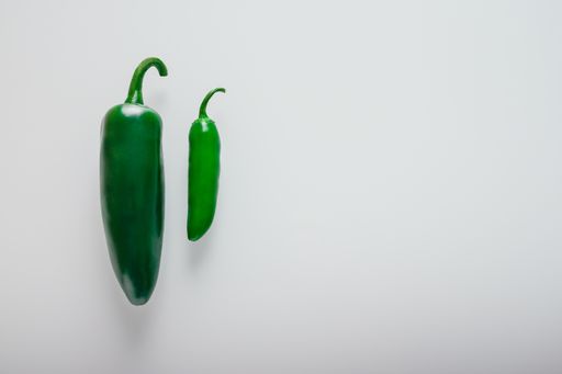 An overhead shot of green jalapeno chili peppers isolated on a white background