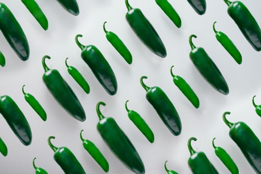 An overhead shot of green jalapeno chili peppers isolated on a white background
