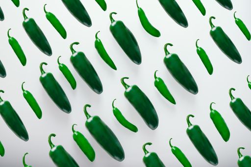 An overhead shot of green jalapeno chili peppers isolated on a white background
