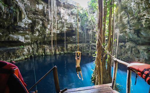 Travelers enjoy a rope swing at Cenote San Lorenzo Oxman, a scenic cenote in Mexico's Yucatan region.