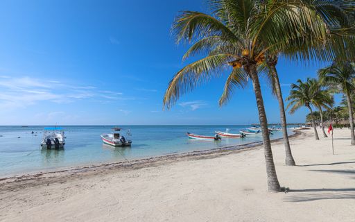 Boats float on the emerald waters at Akumal Beach in Mexico's Riviera Maya.