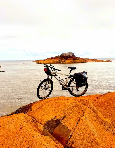 A vertical shot of a GT bicycle parked on a huge rock in the background of the sea in Chile.
