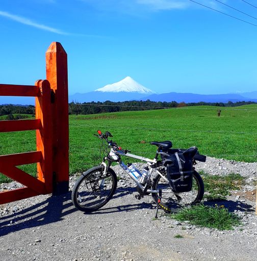 A close-up shot of a bike parked next to a wooden railing in the background of a green field in Chile.