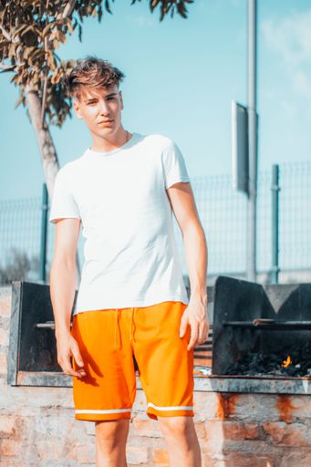 A vertical shot of a young Caucasian man cooking on a barbecue outdoors in a park by the road