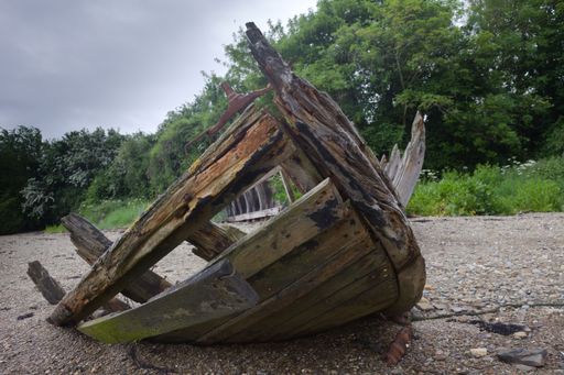 An old broken wooden boat on a rocky beach