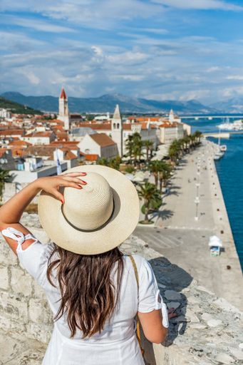 A stylish female in a straw hat observing the beautiful seaside town of Trogir in Croatia