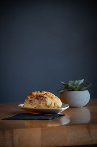 A vertical shot of an apple dumpling on a plate next to an artificial plant on a table