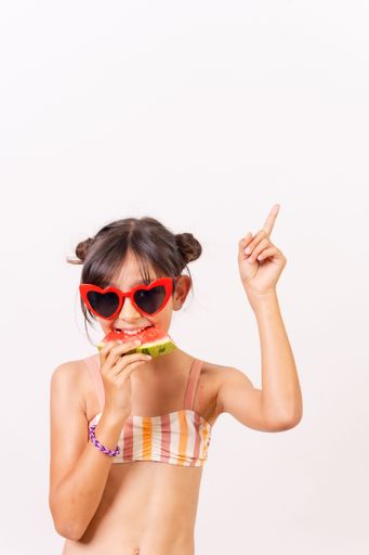 A portrait of a Caucasian girl eating watermelon on a white background-summer vacation concept