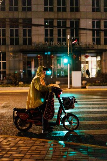 A vertical shot of people going on with their lives in the street of Shanghai, China during nighttime
