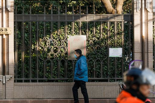 A Chinese man walks down the street with shaped metal fence on the background