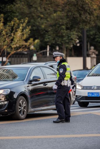 A vertical shot of a policeman regulating traffic on a road in Shanghai, China