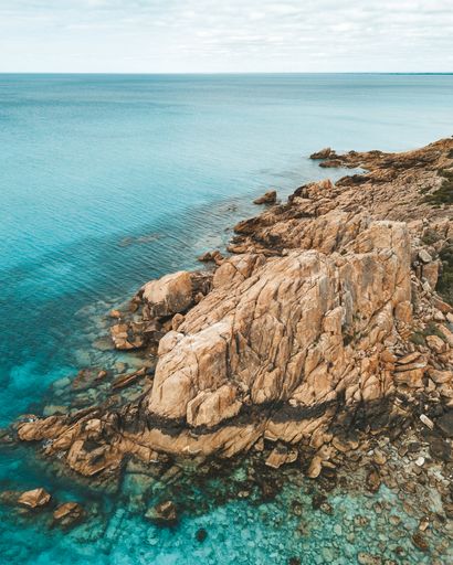 A vertical shot of rocky cliffs and clear seawater