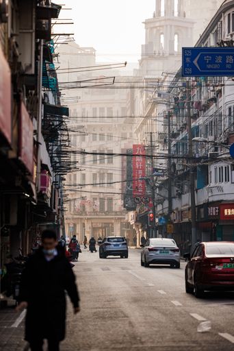 A vertical shot of people walking on the streets of Shanghai with buildings in the background