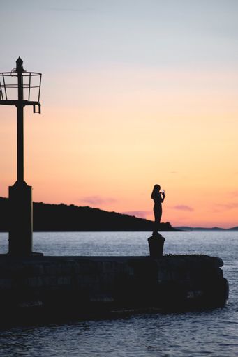 A vertical shot of a woman taking a photo of the sea with her smartphone