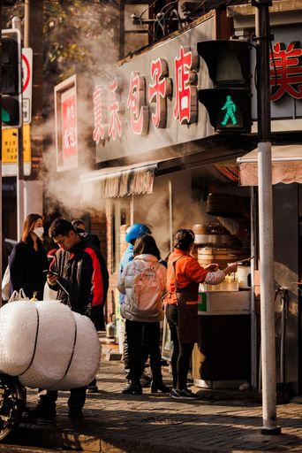 A vertical shot of people standing near a steamed dumpling shop during sunset in Shanghai, China
