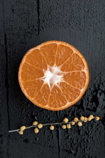 A beautiful top view of an orange slice against black wooden background