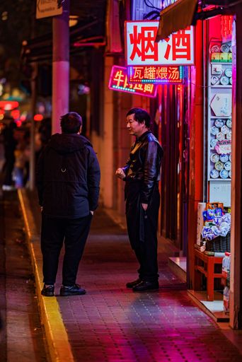 A vertical shot of people near illuminated neon signs at night in Shanghai, China
