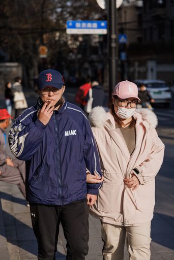 A vertical shot of a stylish cool young couple with the male smoking on the streets of Shanghai, China