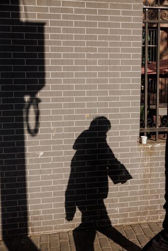 A vertical shot of a person shadow on a sunny brick wall in Shanghai, China