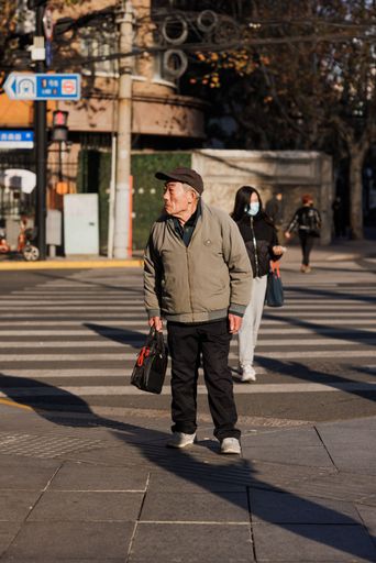 A vertical shot of an older male on a sunny sidewalk near the IAPM mall in Shanghai, China