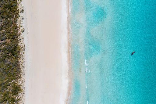 An aerial drone shot of a heavenly sandy beach and crystal clear, teal ocean water