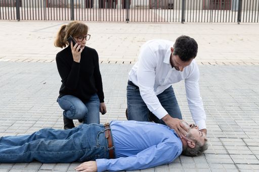 The passers helping an unconscious man outdoors - first aid concept