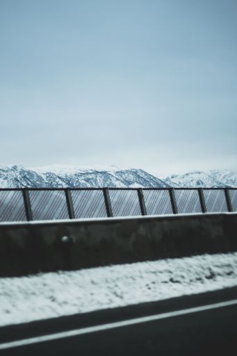 A vertical shot of a mountain range covered with snow on a cloudy day against a road in Austria