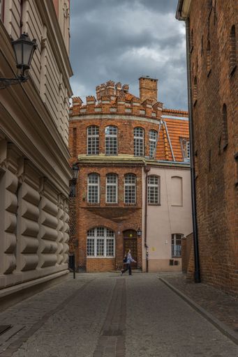 A vertical shot of a narrow alley between traditional stone buildings in Torun, Poland