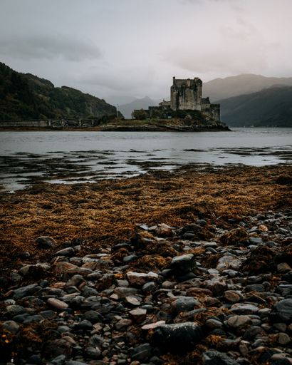 A vertical shot of the Eilean Donan Castle over a pond on a gloomy day in the Isle of Skye, Scotland