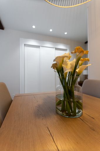 A vertical shot of a glass flower vase on wooden table in a room of modern apartment
