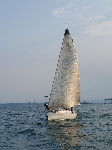 A vertical shot of a white sailboat on the water in Thunder Bay, Canada
