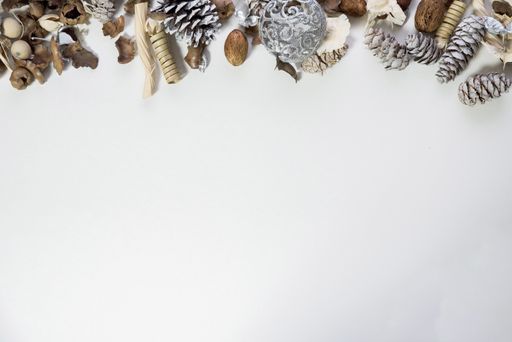 An overhead shot of pine cones and an ornament on the top of a white surface great for writing holiday text