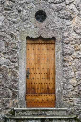 A vertical shot of an old concrete building with a wooden door