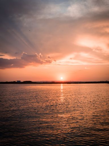 A beautiful vertical shot of a pink sunset over a sea- perfect for mobile wallpaper