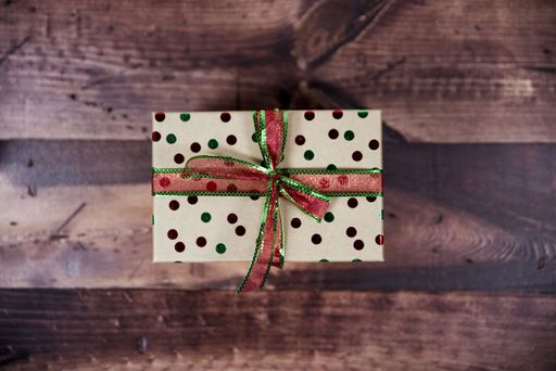 An overhead shot of a present with ribbon on a wooden surface