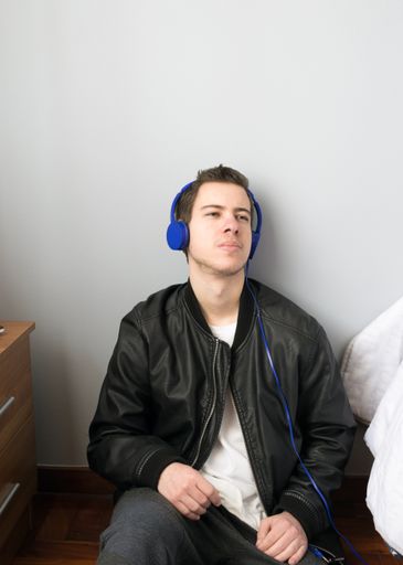 A vertical shot of male model enjoying music in his room