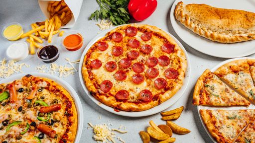 A top view of pizzas served with French fries on a table