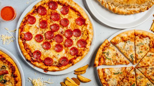 A top view of pizzas served with French fries on a table