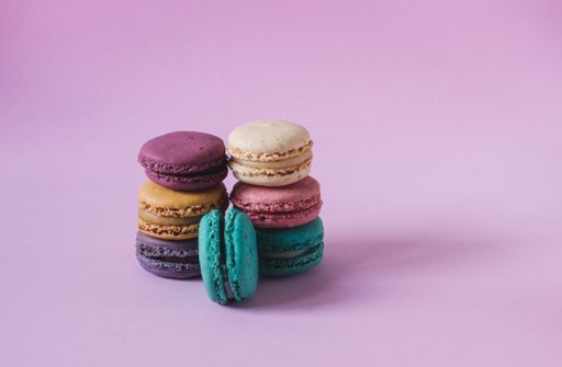 A closeup shot of stacks of colorful macarons on a pink background